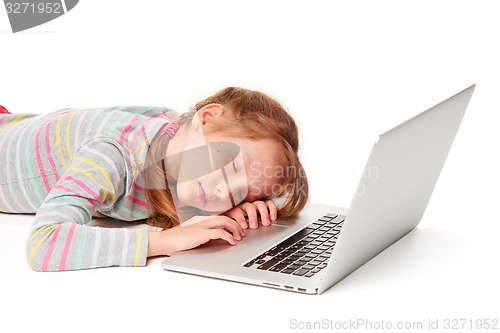 Image of Exhausted little gir sleeping on laptop keyboard