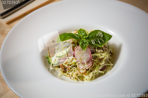 Image of Salad from cabbage, herbs, cucumber and radish in bowl.