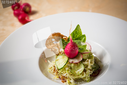 Image of Salad from cabbage, herbs, cucumber and radish in bowl.