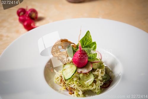 Image of Salad from cabbage, herbs, cucumber and radish in bowl.