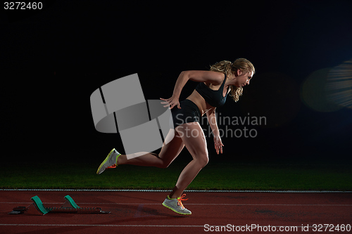 Image of woman  sprinter leaving starting blocks