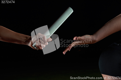 Image of athletic runners passing baton in relay race