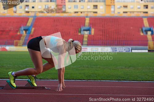 Image of woman  sprinter leaving starting blocks