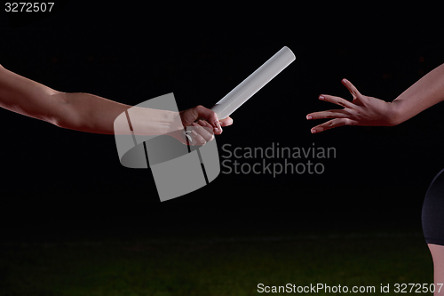 Image of athletic runners passing baton in relay race