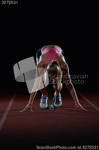 Image of woman  sprinter leaving starting blocks