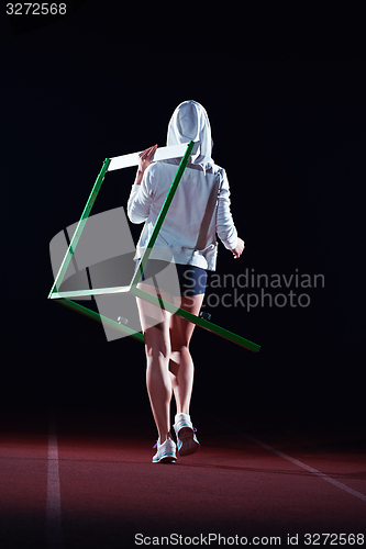 Image of woman athlete jumping over a hurdles