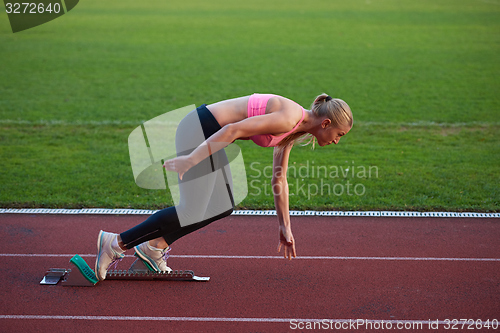 Image of woman  sprinter leaving starting blocks