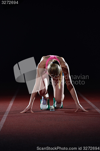 Image of woman  sprinter leaving starting blocks