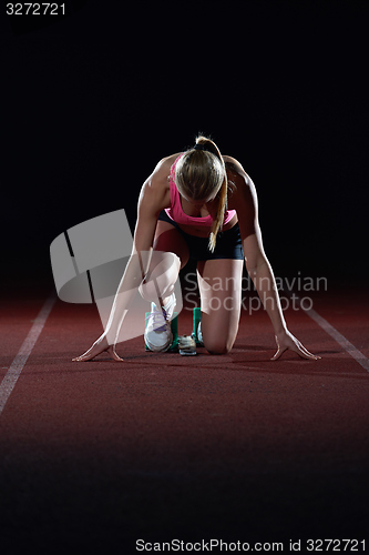 Image of woman  sprinter leaving starting blocks