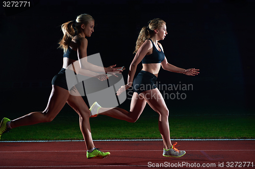 Image of athletic runners passing baton in relay race