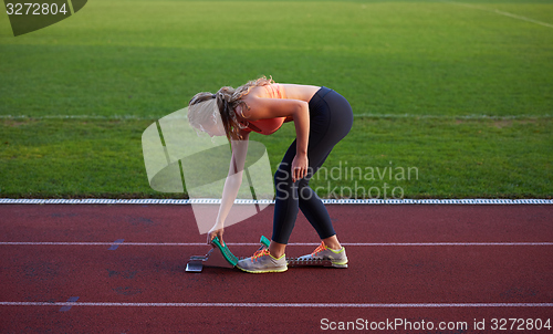 Image of woman  sprinter leaving starting blocks