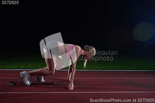 Image of woman  sprinter leaving starting blocks