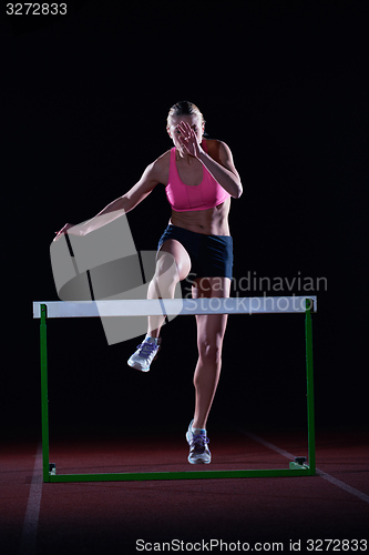 Image of woman athlete jumping over a hurdles