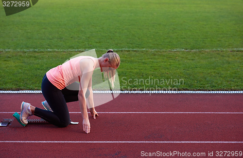 Image of woman  sprinter leaving starting blocks