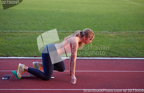 Image of woman  sprinter leaving starting blocks