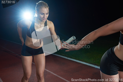 Image of athletic runners passing baton in relay race