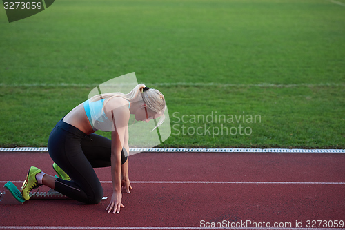 Image of woman  sprinter leaving starting blocks