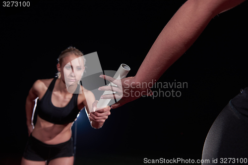 Image of athletic runners passing baton in relay race