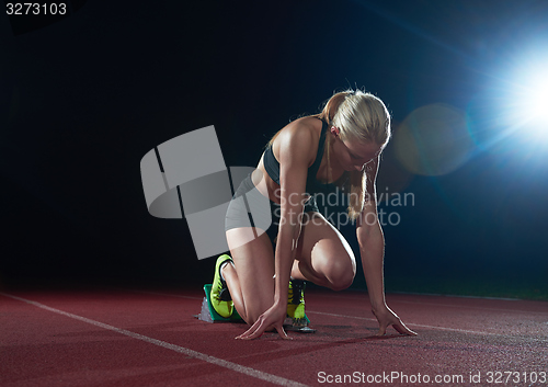 Image of woman  sprinter leaving starting blocks