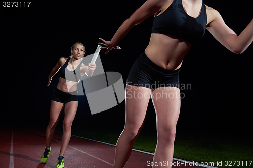 Image of athletic runners passing baton in relay race