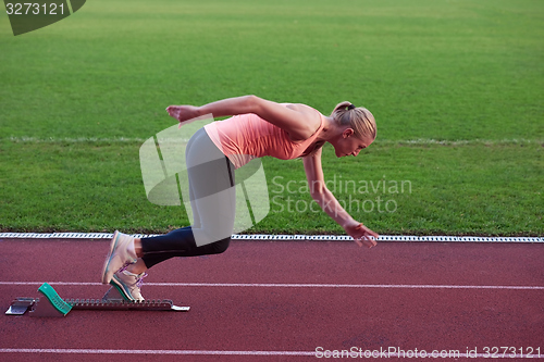 Image of woman  sprinter leaving starting blocks