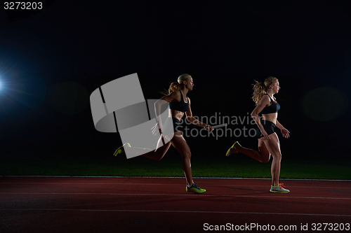 Image of athletic runners passing baton in relay race