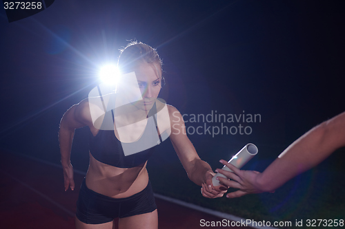 Image of athletic runners passing baton in relay race