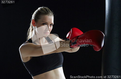Image of beautiful woman is boxing on black background
