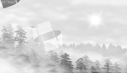 Image of UFO in a landscape of misty forest at sunrise