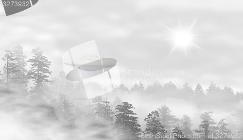 Image of UFO in a landscape of misty forest at sunrise