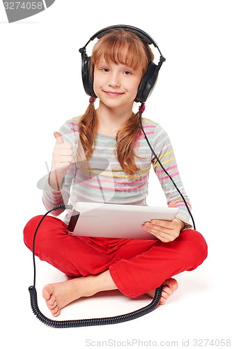 Image of Little girl enjoying music listening in headphones