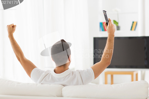 Image of man watching tv and supporting team at home