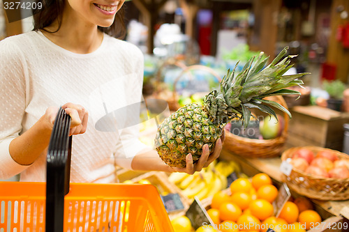 Image of close up of woman with pineapple in grocery market