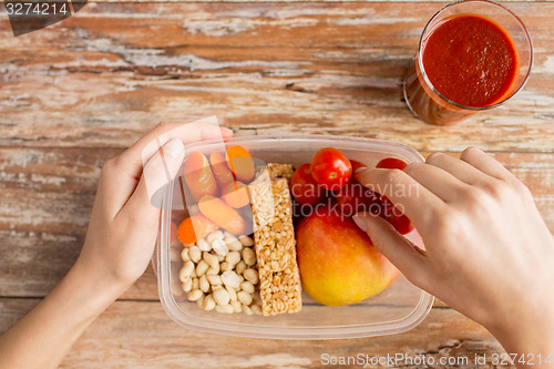 Image of close up of hands with vegetarian food in box