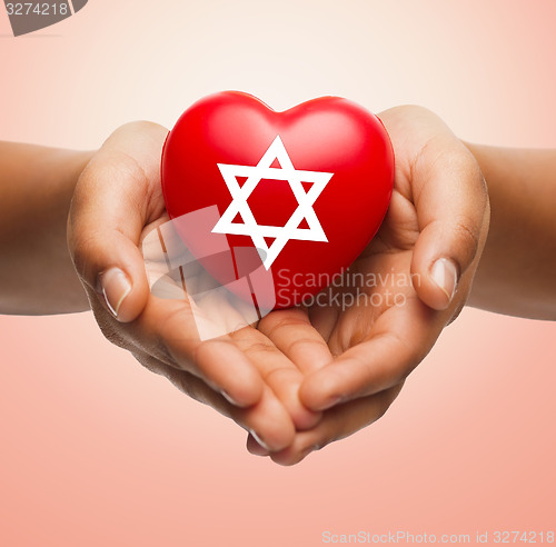 Image of close up of hands holding heart with jewish star