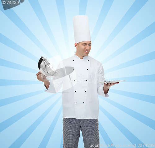 Image of happy male chef cook opening cloche