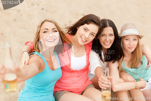 Image of smiling girls with drinks on the beach