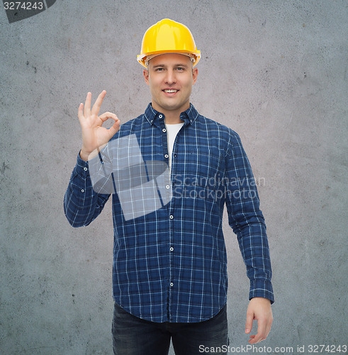 Image of smiling male builder in helmet showing ok sign
