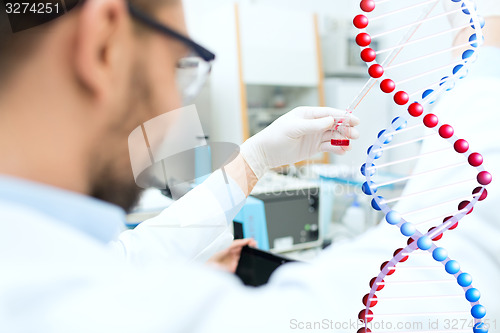 Image of close up of scientist with tube and pipette in lab