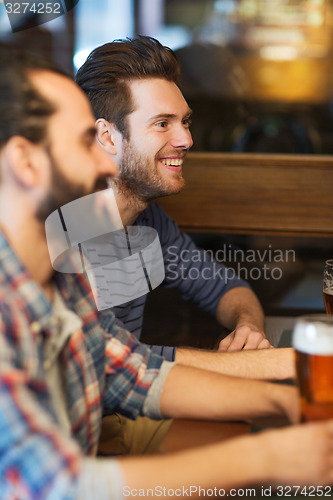 Image of happy male friends drinking beer at bar or pub