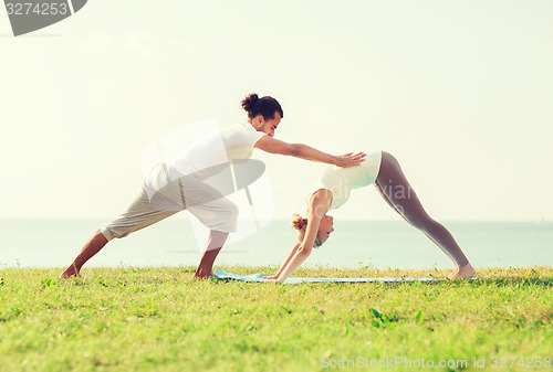 Image of smiling couple making yoga exercises outdoors