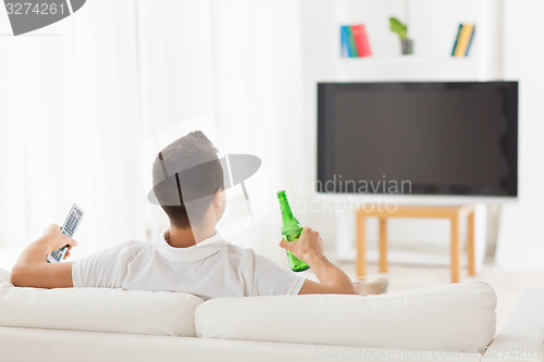 Image of man watching tv and drinking beer at home