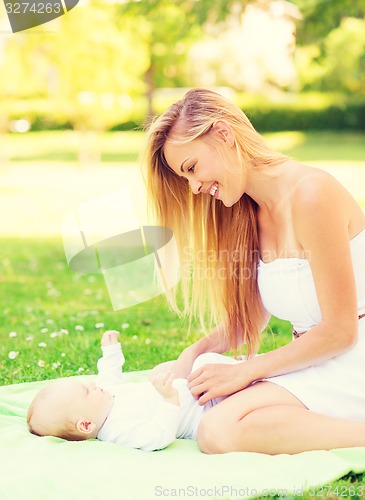 Image of happy mother lying with little baby on blanket