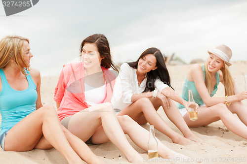 Image of smiling girls with drinks on the beach