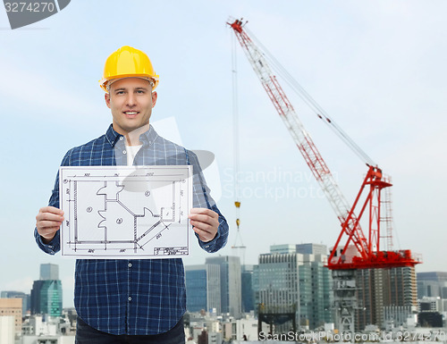 Image of smiling male builder in helmet with blueprint