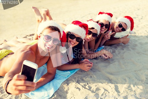 Image of group of friends in santa hats with smartphone