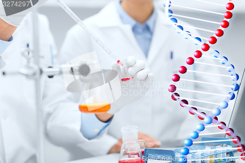 Image of close up of scientists filling test tube in lab