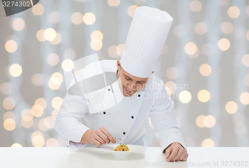 Image of happy male chef cook decorating dish