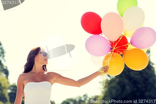 Image of smiling young woman in sunglasses with balloons