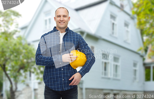 Image of smiling man holding helmet over house background